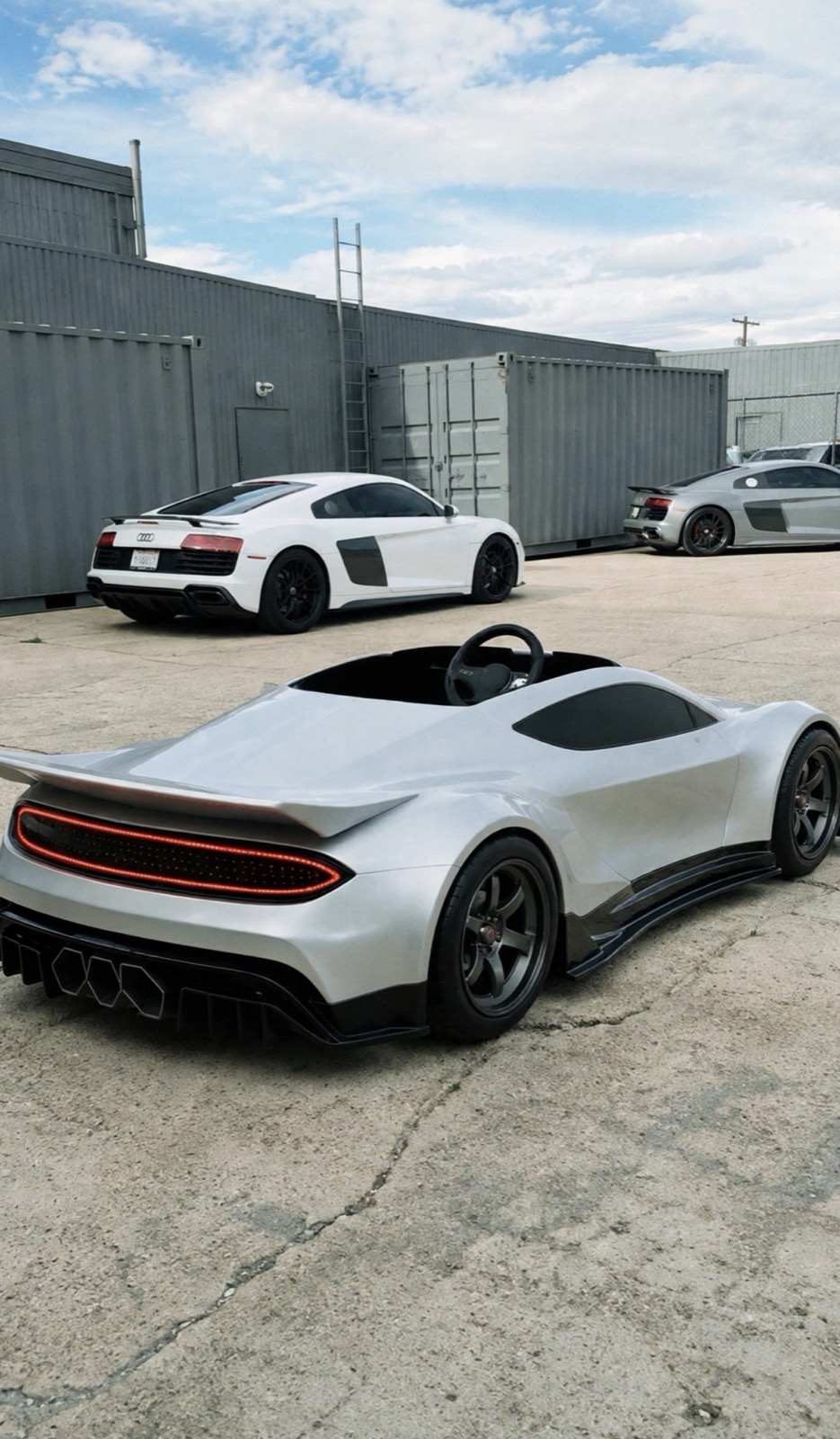GENOS R1 outdoors alongside full-size performance cars